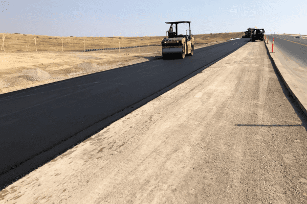 HEI Civil Colorado 2021 144th Job Site HEI Civil worker rolls on asphalt roller on a newly paved road at the 144th job site.
